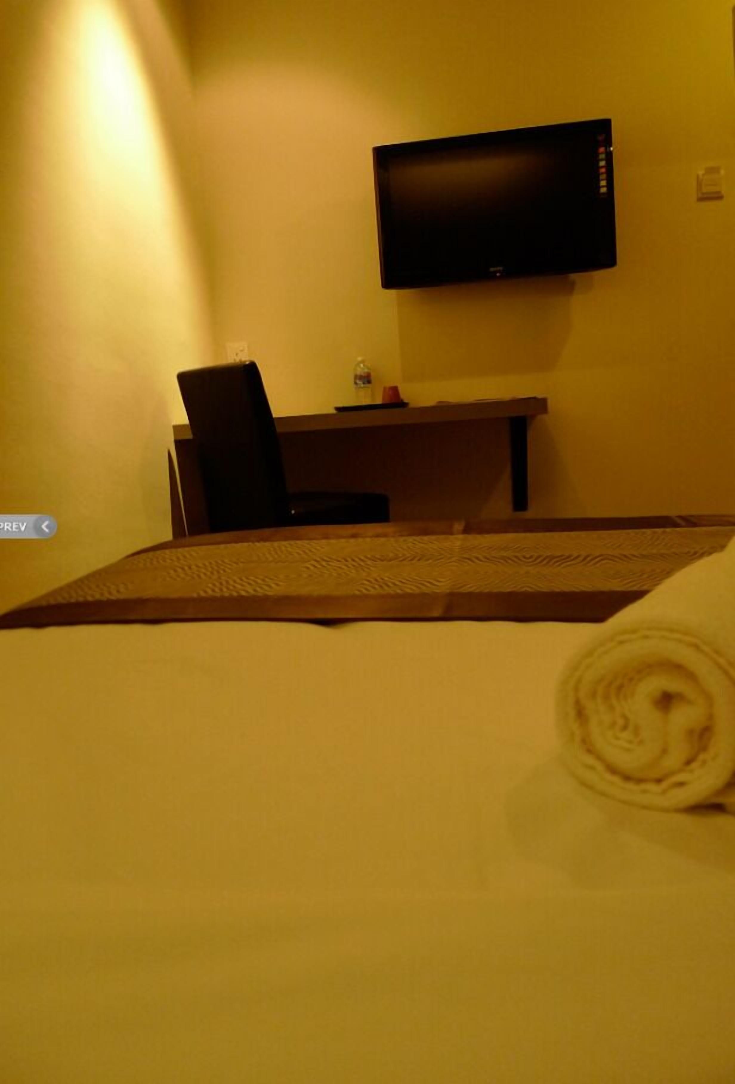 Habitación de hotel con una cama, un escritorio, una silla y un televisor de pantalla plana montado en la pared.