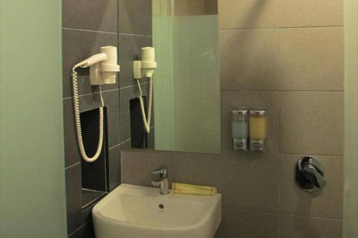 Een badkamer met een wastafel, spiegel en twee zeepdispensers.
