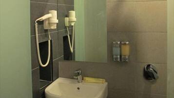A bathroom with a sink, mirror, and two towel dispensers.