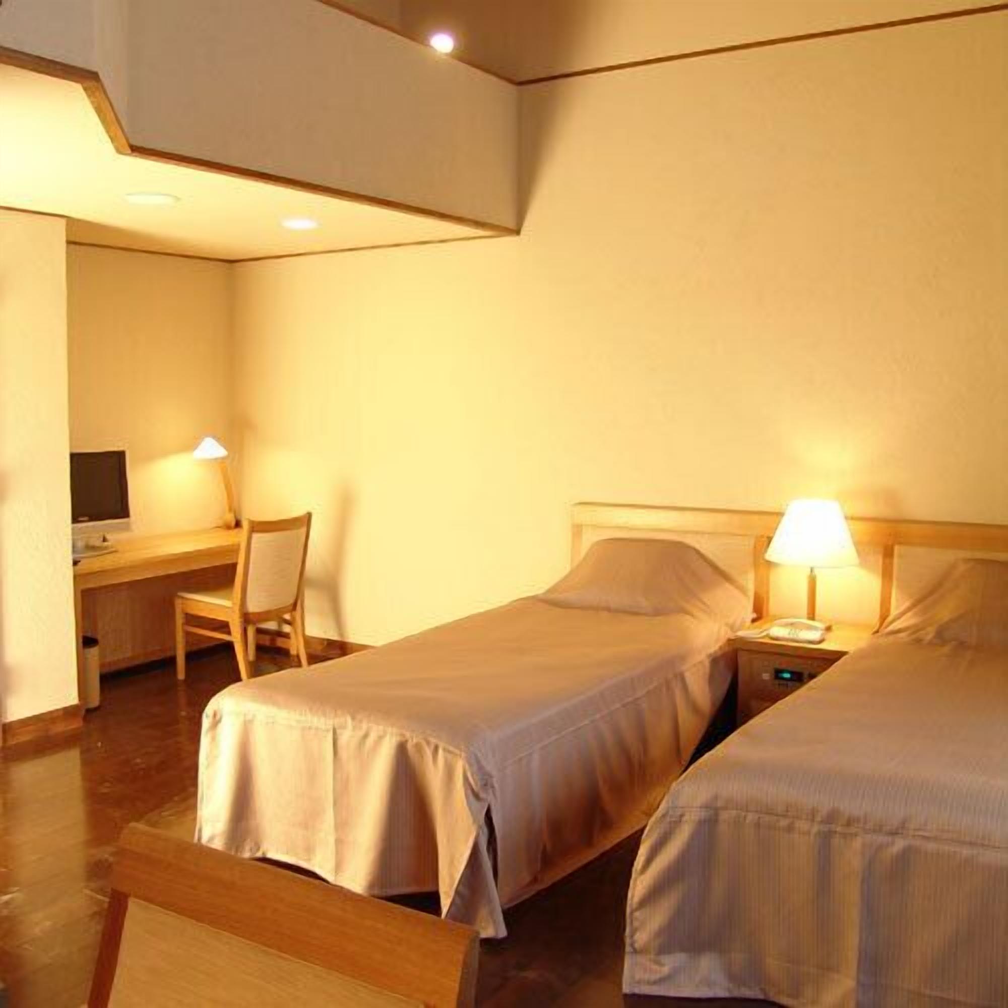 Une chambre d’hôtel avec deux lits, un bureau et une chaise.