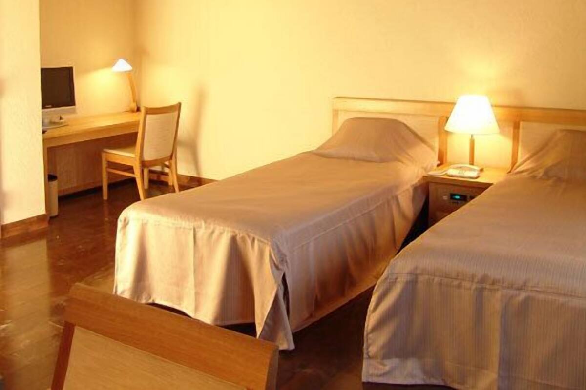 Ein Hotelzimmer mit zwei Betten, einem Schreibtisch und einem Stuhl.