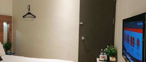 A hotel room with a bed, a wardrobe, a small table with a plant, and a TV on the wall.