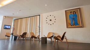 Un vestíbulo amplio con sillas modernas, un reloj grande y un retrato enmarcado en la pared.