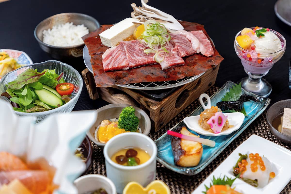 Diversos platos, incluyendo carne a la parrilla, arroz y un postre con helado y fruta.