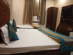 Une chambre d’hôtel avec un lit, une armoire, une télévision et une fenêtre avec des rideaux.