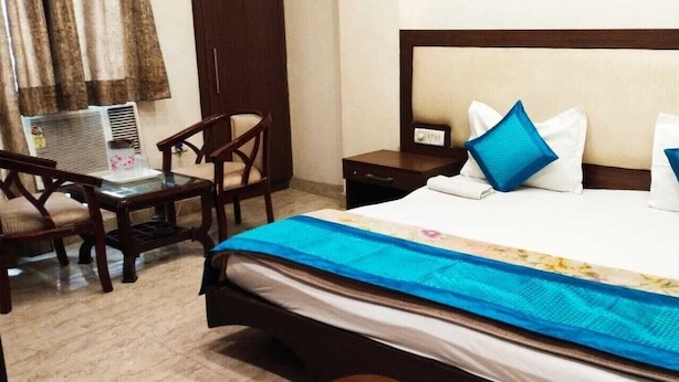 A hotel room with a bed, a desk, and a chair. - Indo Continental (Delhi)