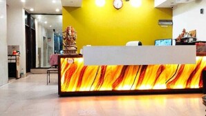 A reception desk with a marble-like design, a clock on the wall, and a statue in the background. - Indo Continental (Delhi)