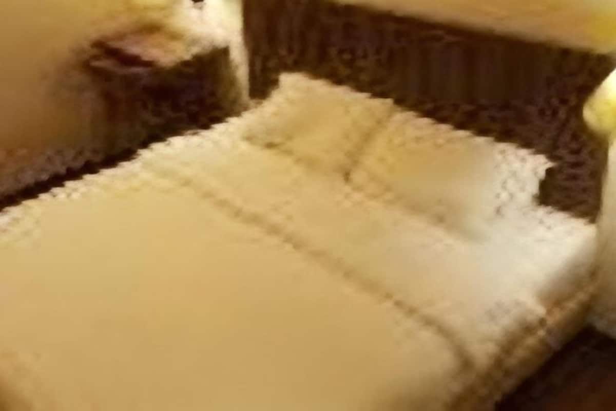 Una cama con cubierta blanca, una mesita de noche y una lámpara.