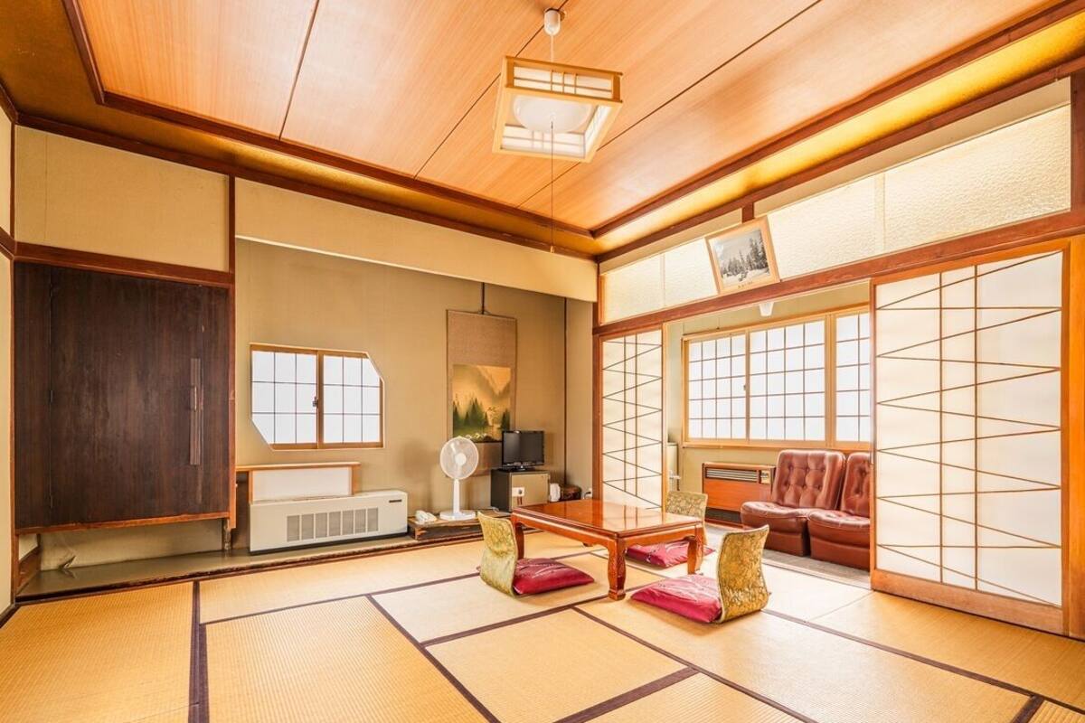 Une pièce de style japonais traditionnel, avec un sol recouvert de tatamis, une table basse, des coussins et des portes coulissantes.