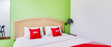 Una habitación de hotel con cama, paredes verdes y una colcha roja y blanca.
