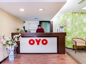 Un comptoir d’accueil avec une enseigne indiquant « OYO » et une personne debout derrière.