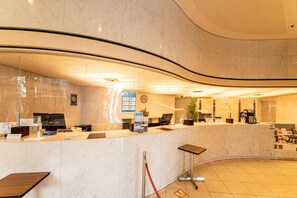 Eine Hotelrezeption mit Marmorzauber, Computern und einer Wanduhr.