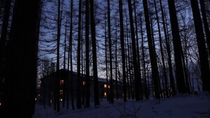 A forested area with tall trees and a building with multiple windows. - Tokachi Sahoro Resort (Shintoku)