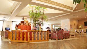 A lobby with a reception desk, plush chairs, a large plant, and a television on the left. - Tokachi Sahoro Resort (Shintoku)