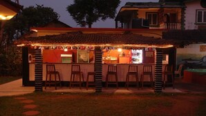 A bar with a tiled roof, outdoor seating, and a counter. - Lua Nova (Baga)