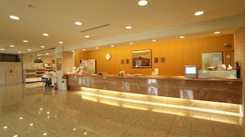 A hotel reception area with a polished marble counter, a clock, and a computer monitor.