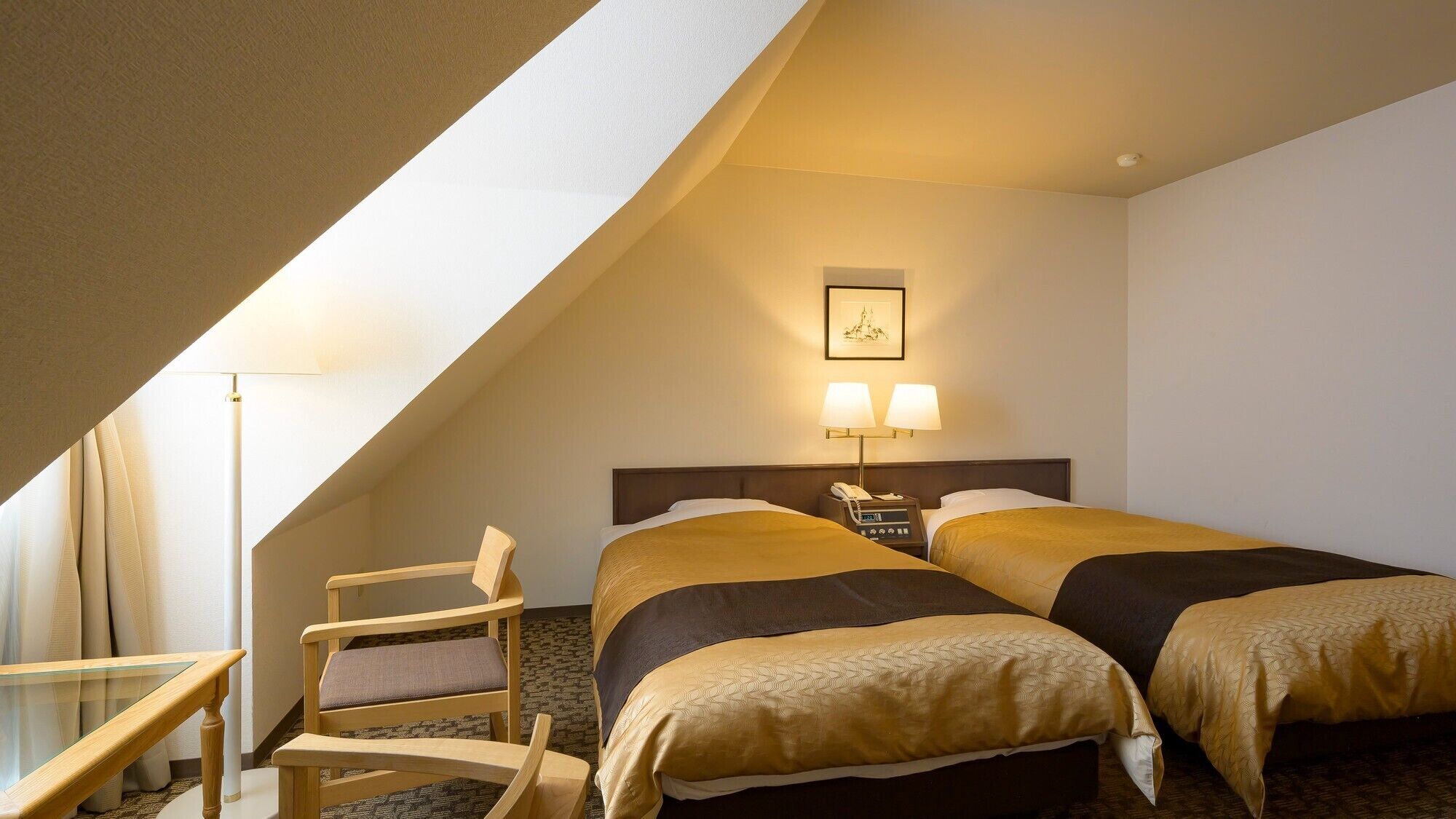 A hotel room with two beds, a desk, a chair, and a picture on the wall.