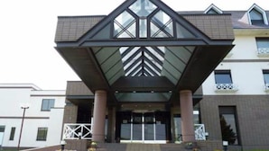 A modern building with a distinctive triangular roof structure and a central entrance with steps leading up to it. - Hotel Edel Warme (Furano)