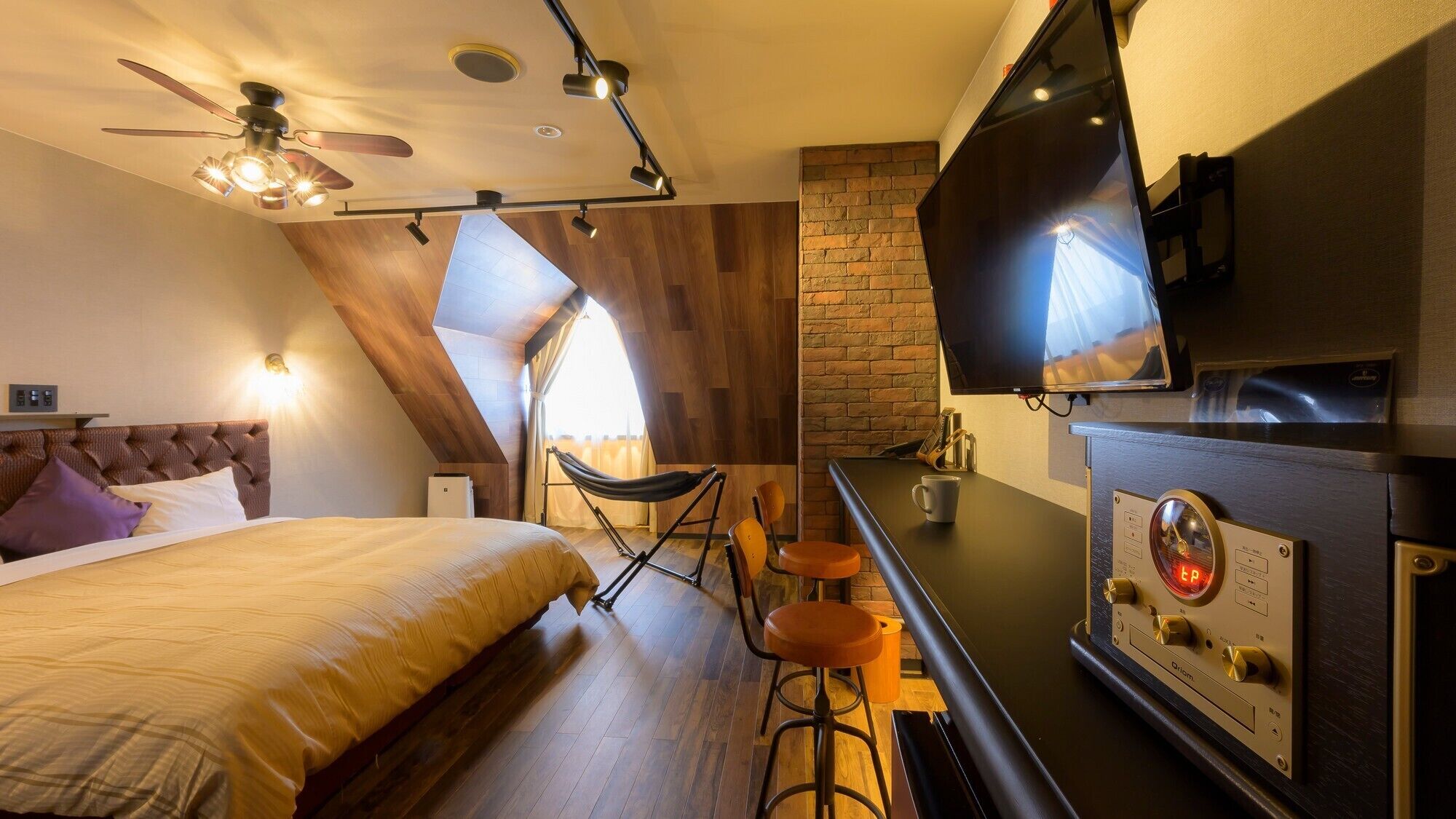 A modern hotel room with a bed, a TV, a coffee machine, and a bar area.