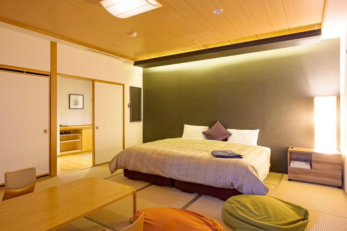 Une chambre d’hôtel comprenant un lit, une table de chevet, une chaise et une petite table.