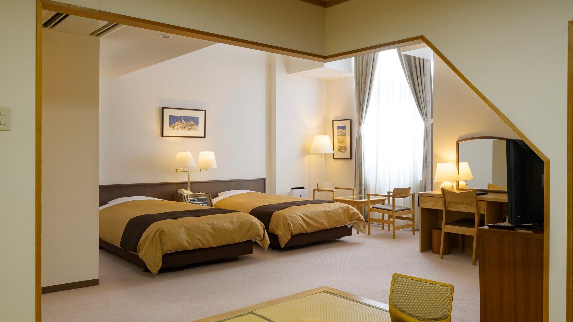 A hotel room with two beds, a desk, a chair, a TV, and a picture on the wall.
