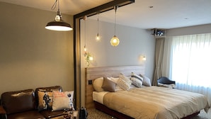 A modern hotel room with a large bed, a leather sofa, a wooden coffee table, and a mirror. - Hotel Edel Warme (Furano)