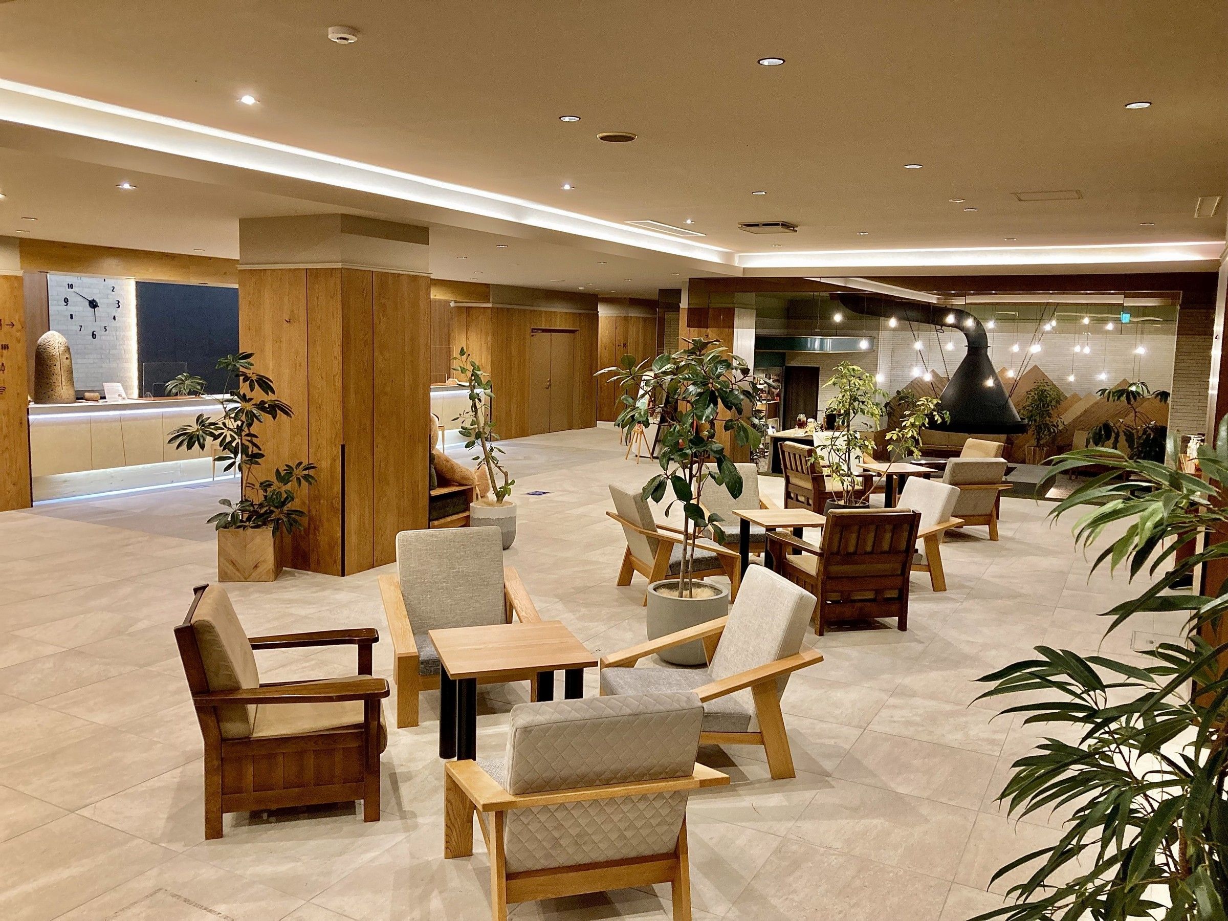 A spacious lobby with multiple seating areas, wooden furniture, and potted plants.