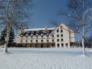 Ein mehrgeschossiges Gebäude mit schneebedecktem Dach und einer symmetrischen Fassade.