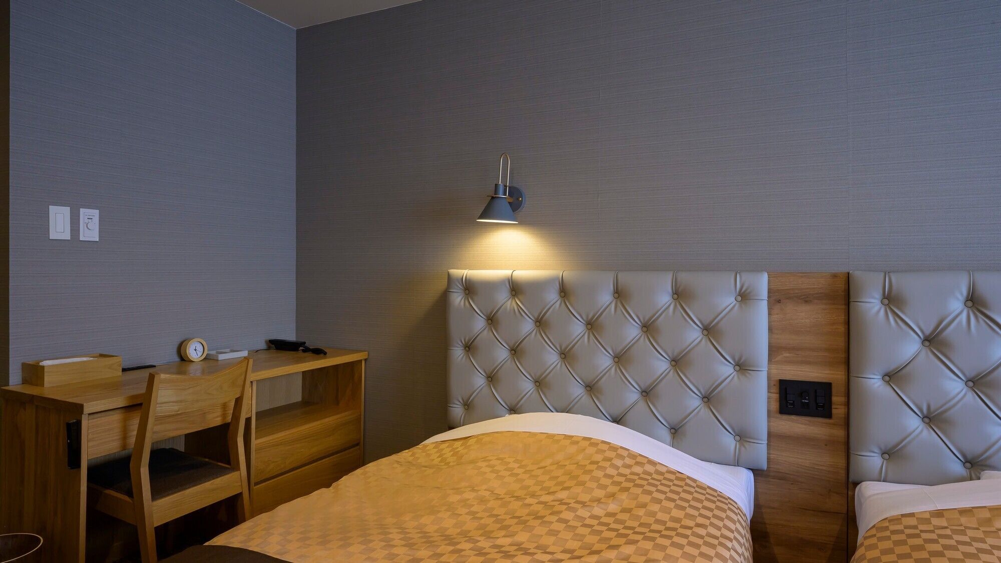 A hotel room with a bed, a desk, and a chair.