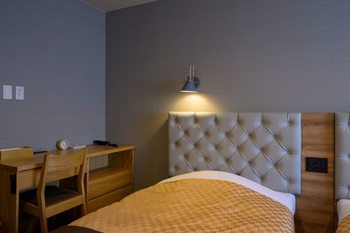 Une chambre d’hôtel avec un lit, un bureau et une chaise.