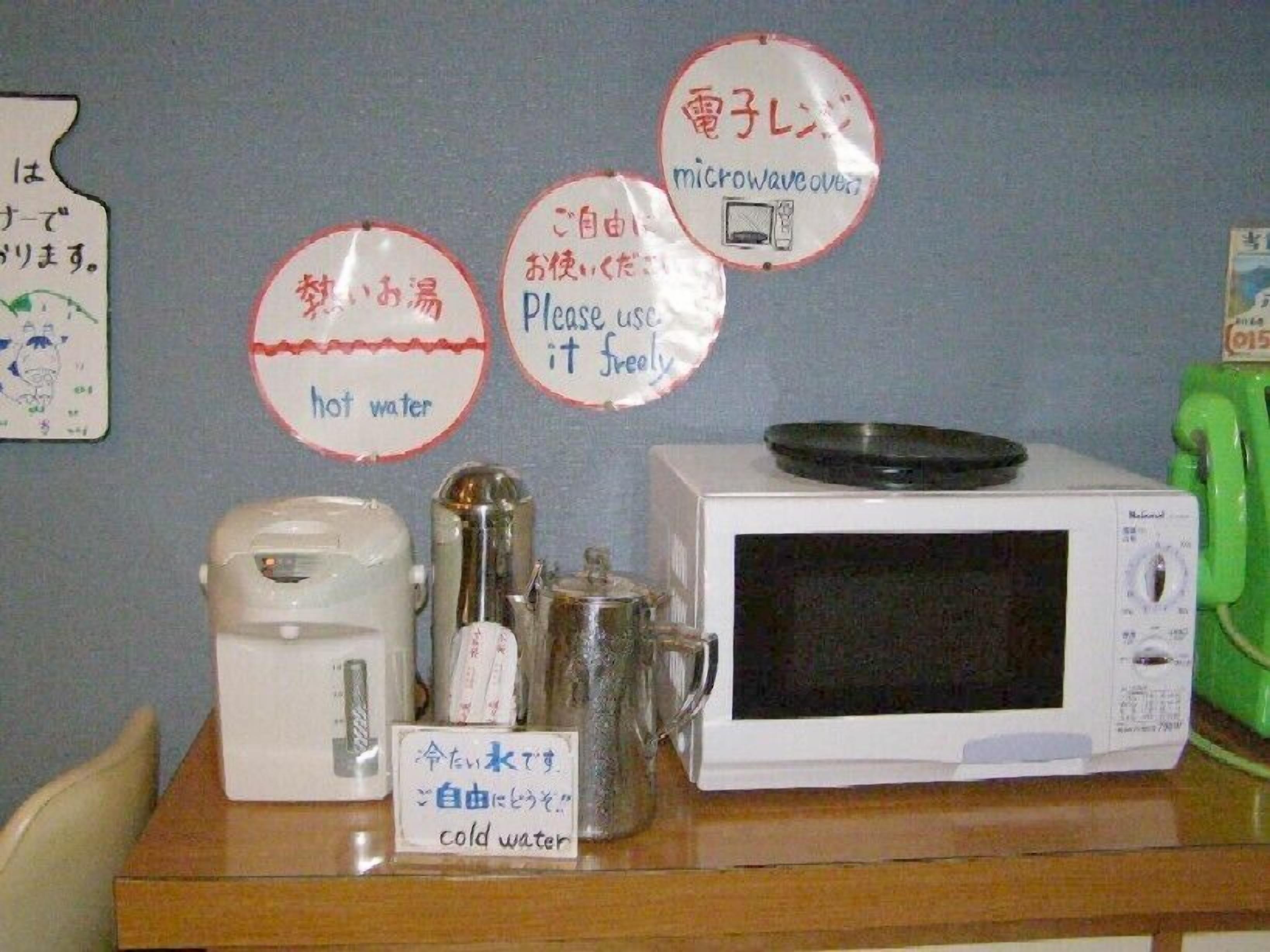 Una cocina compacta con microondas, hervidor de agua y un letrero que señala agua caliente y fría.