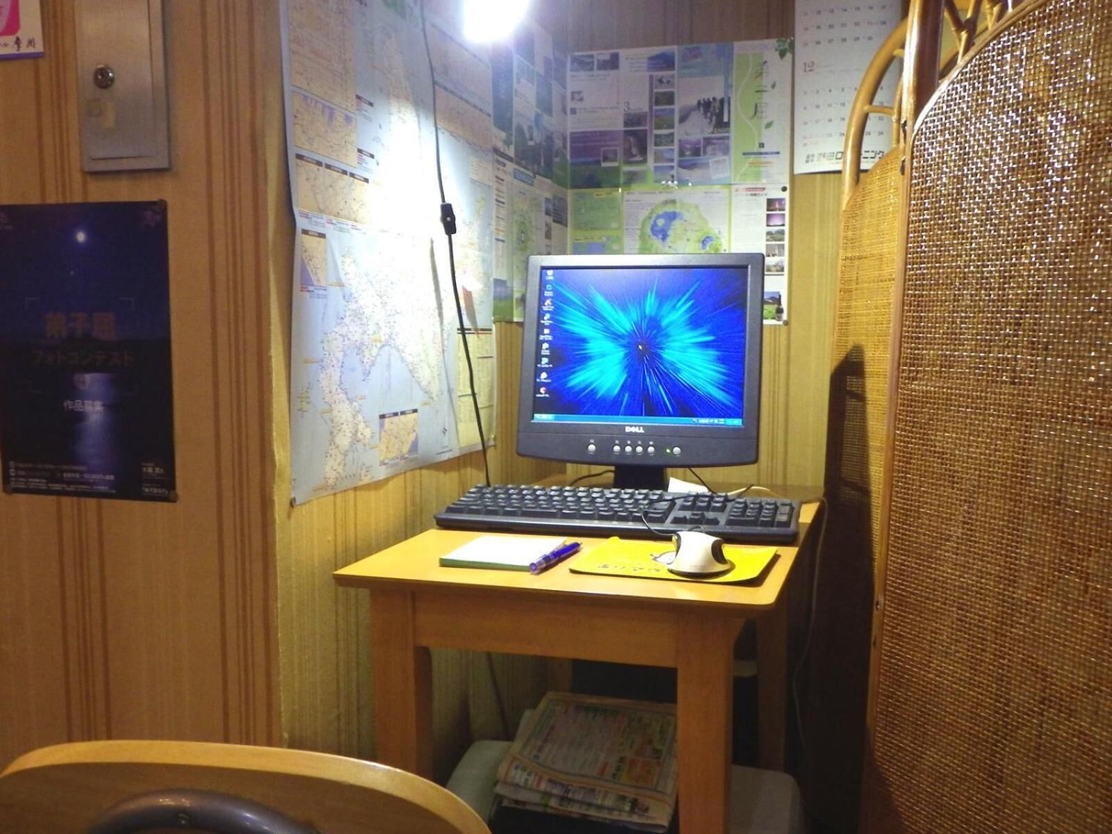A small office with a computer, keyboard, mouse, and a map on the wall.