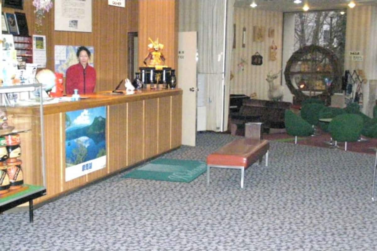 A reception area with a wooden counter, a bench, and a poster of a landscape.
