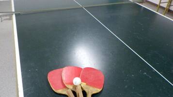 A table tennis table with two red paddles and a white ball.