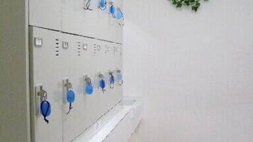 A room with a white cabinet with blue handles, a green trash bin, and a wreath on the wall.
