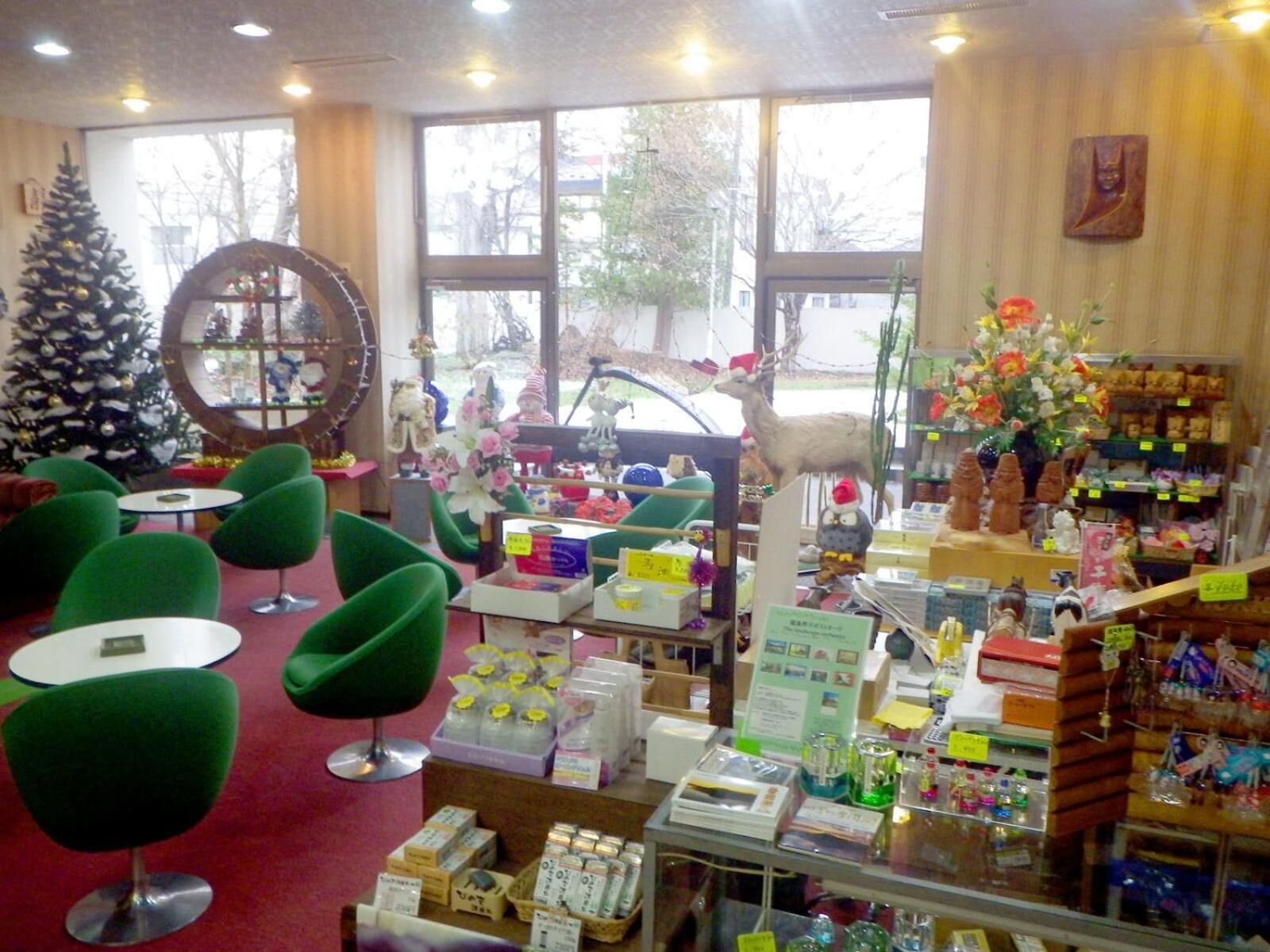 Un interior acogedor con sillas verdes, un árbol de Navidad y varios objetos en estantes.