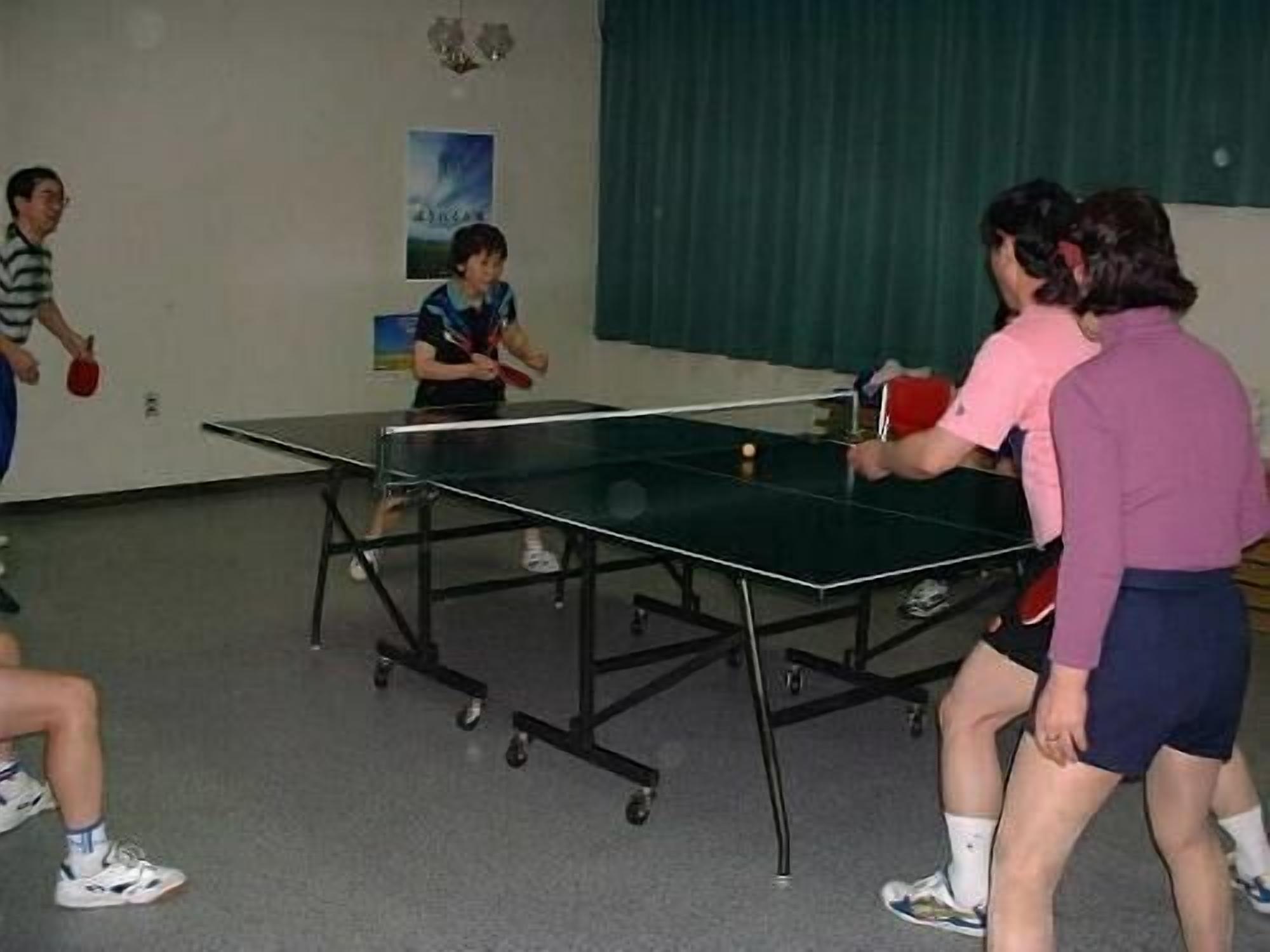 A table tennis table in a room with a green curtain and a poster on the wall.
