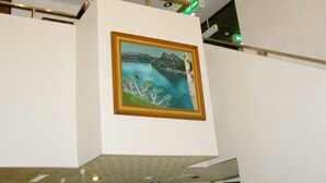 A room with a high ceiling, a framed painting of a landscape, and a visible light fixture. - Hotel Masyu (Teshikaga)