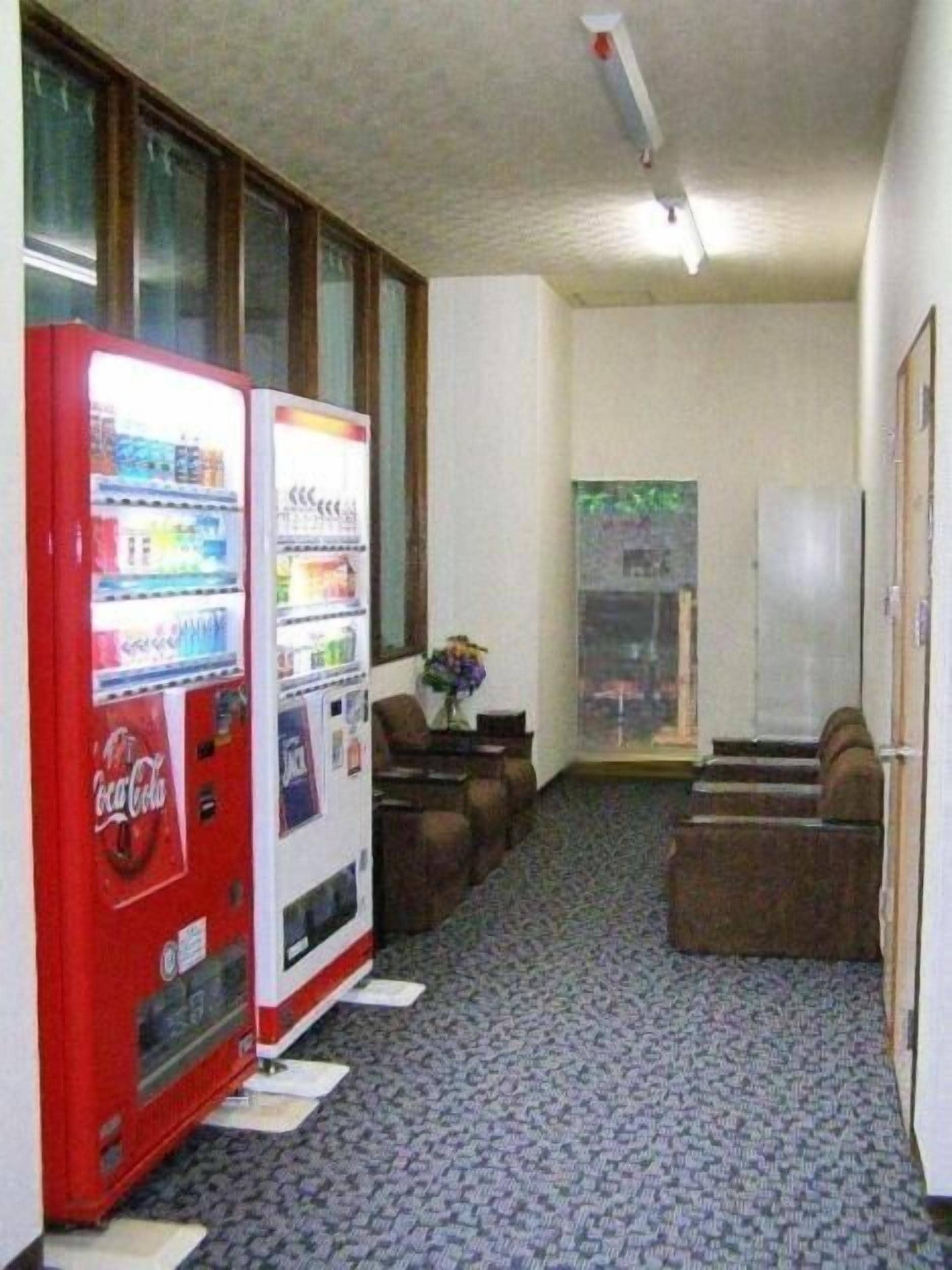 A hallway with vending machines, a carpeted floor, and a door with a glass panel.