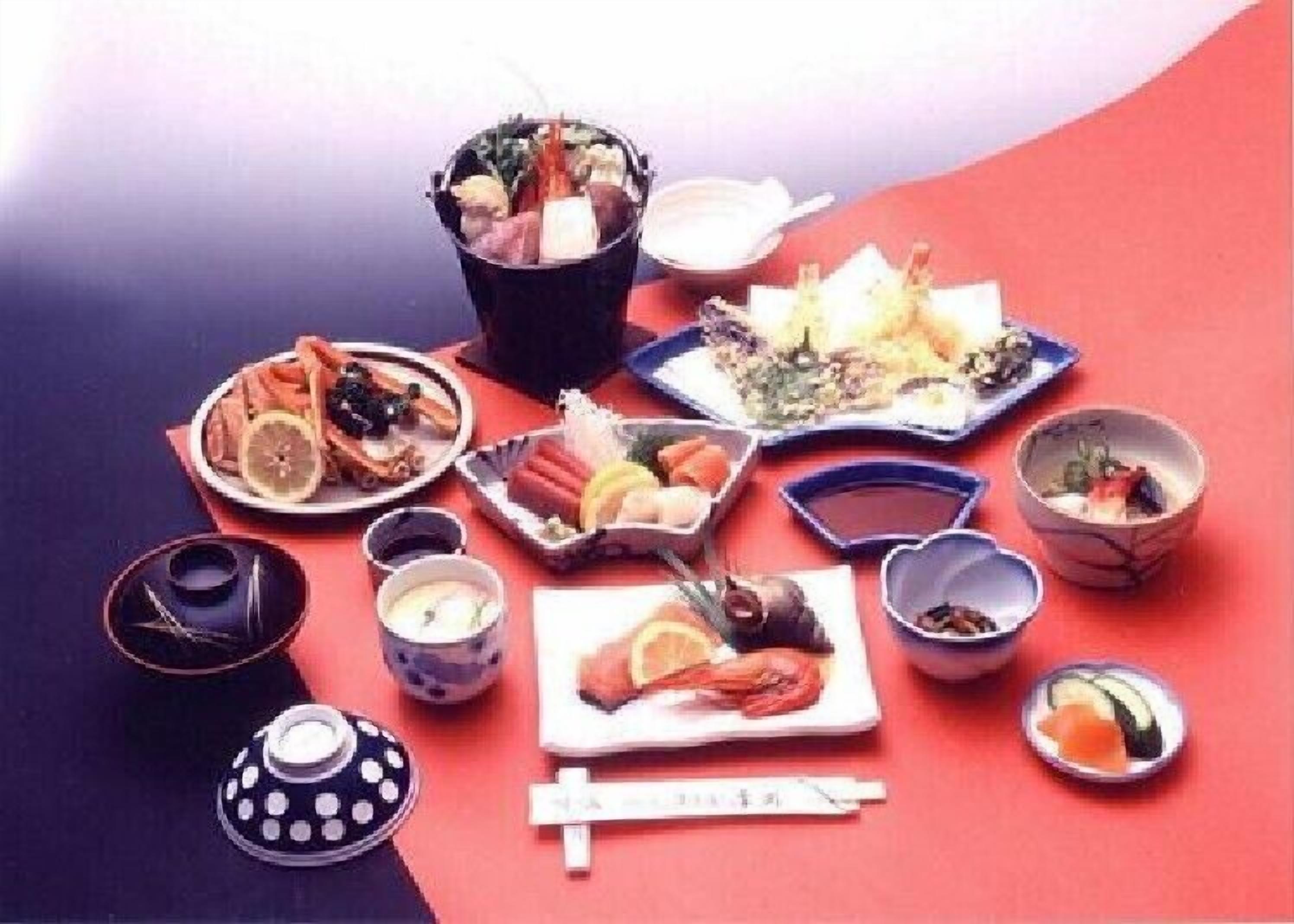 A table with various dishes and drinks, including sushi, sashimi, and bowls of soup.