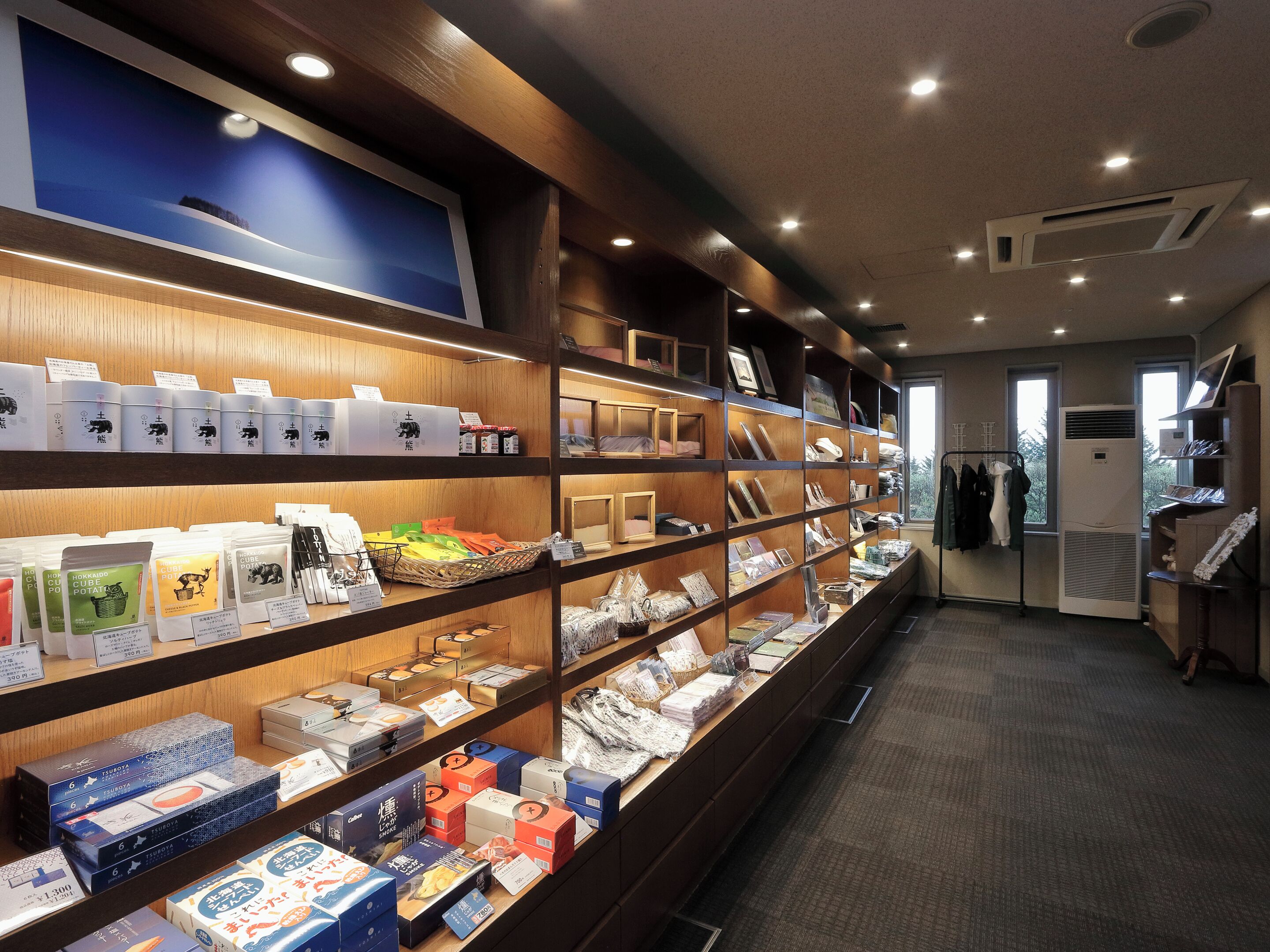 A retail store with shelves stocked with various products, including packaged goods and framed items.