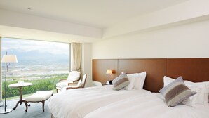 Une chambre d’hôtel avec un grand lit, une chaise, une petite table et une vue sur un paysage par la fenêtre.