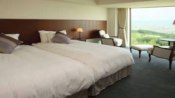 A hotel room with two large beds, a chair, a small table, and a view of the countryside.