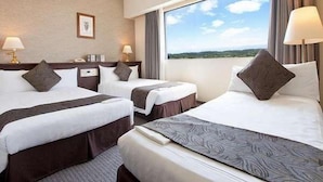 Habitación de hotel con dos camas, un ventanal con vistas y un cuadro en la pared.