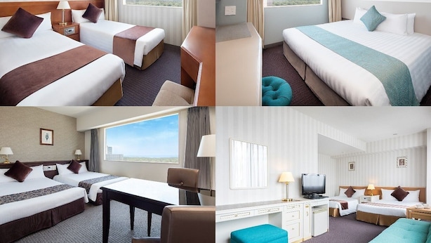 Habitación de hotel con dos camas, un escritorio, televisión y vistas a la ciudad.