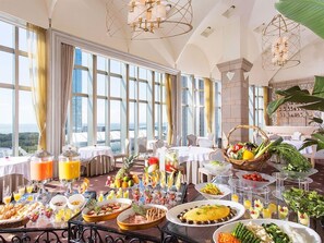 A breakfast buffet with various food items and beverages, set in a room with large windows and a view of the cityscape. - Francs (Chiba)