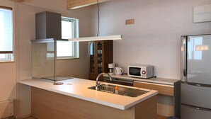 Eine moderne Küche mit einer zentralen Kochinsel, Edelstahlgeräten und Holzbalken an der Decke.