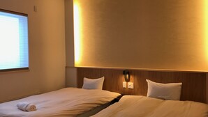 Ein Hotelzimmer mit zwei Betten, einem hölzernen Kopfteil und einer Wandleuchte.
