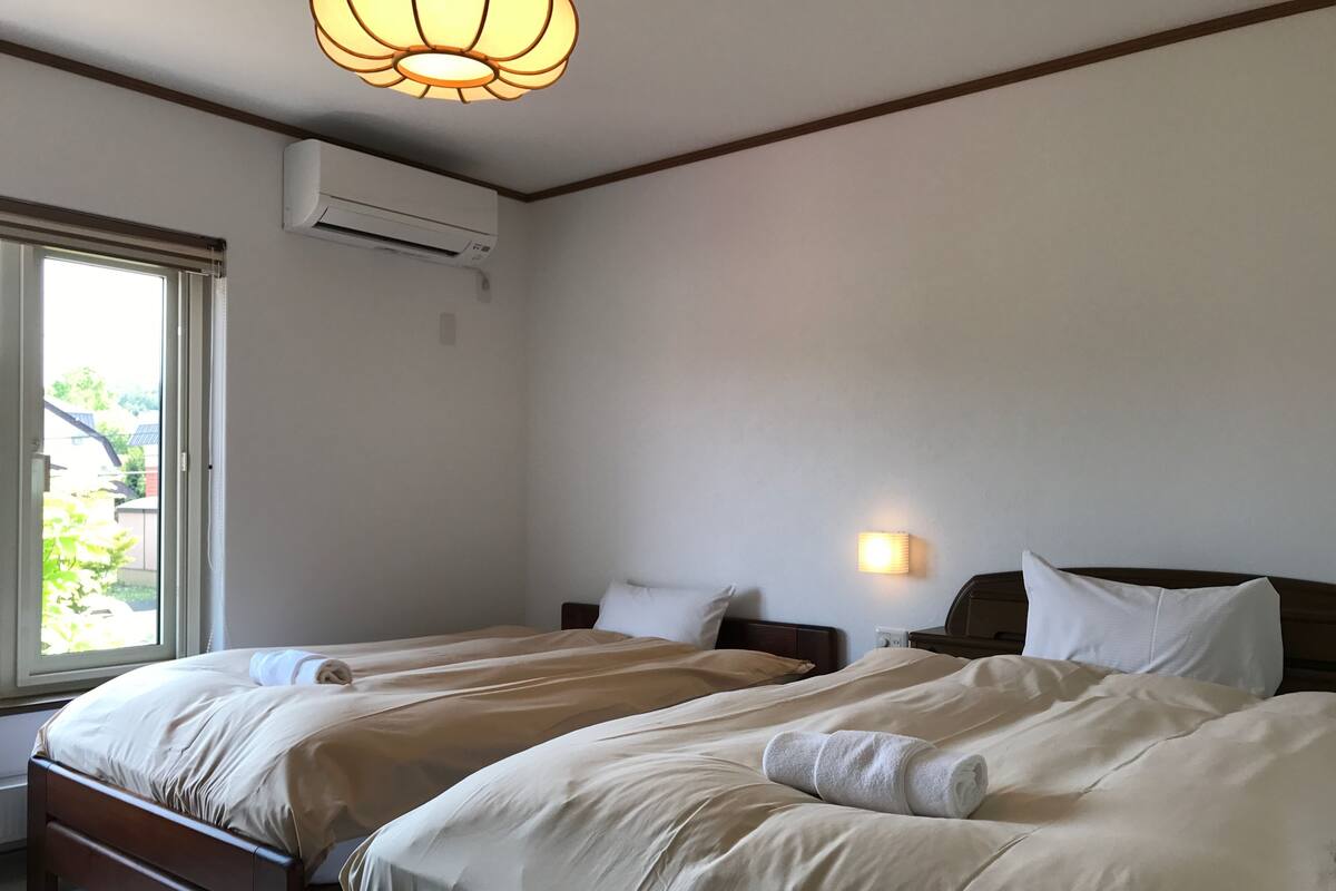 Une chambre d’hôtel avec deux lits, une fenêtre, un appareil de climatisation et un luminaire fixé au mur.