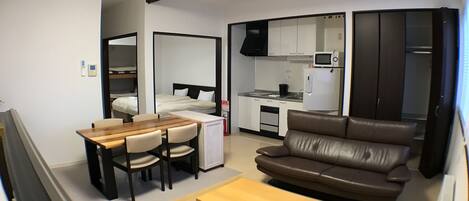 Un espacio habitable compacto con kitchenette, comedor y zona de estar.